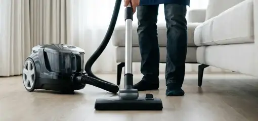 Professional house cleaner vacuuming a living room floor with a canister vacuum cleaner, Chandler, AZ.
