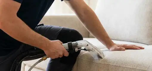 Professional upholstery cleaner deep-cleaning a fabric sofa with a handheld extraction tool, Chandler, AZ.